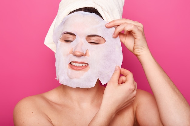 Het binnenschot van jonge vrouw past gezichts kosmetisch masker toe