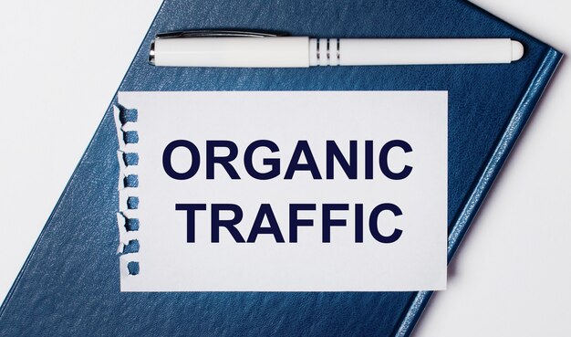 Het blauwe dagboek ligt op een lichte achtergrond. op heeft een witte pen en een vel papier met de tekst organic traffic.