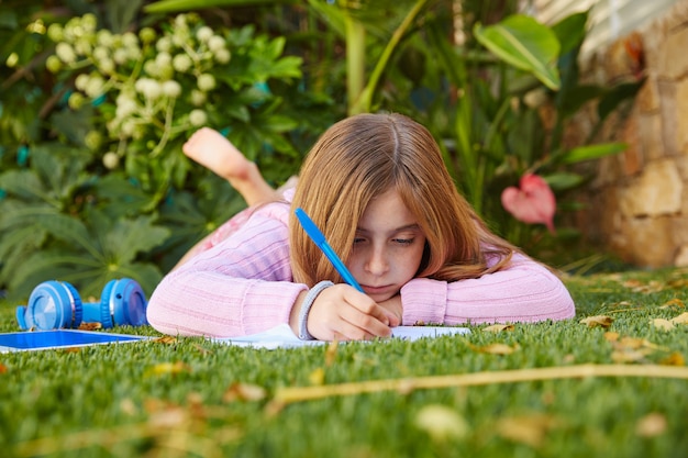 Het blonde thuiswerk die van het jong geitjemeisje op grasgras liggen