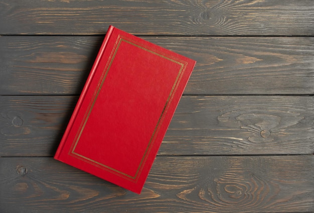 Foto het boek zit in een rode kaft op een grijze houten ondergrond met een plek voor de tekst
