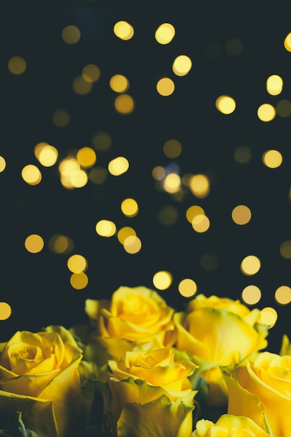Foto het boeket van mooie gele rozen sluit omhoog op dark met slingerlichten.