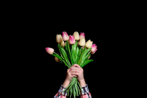 Het boeket van tulpen in kinderenhanden houdt een boeket. Geïsoleerd op zwart