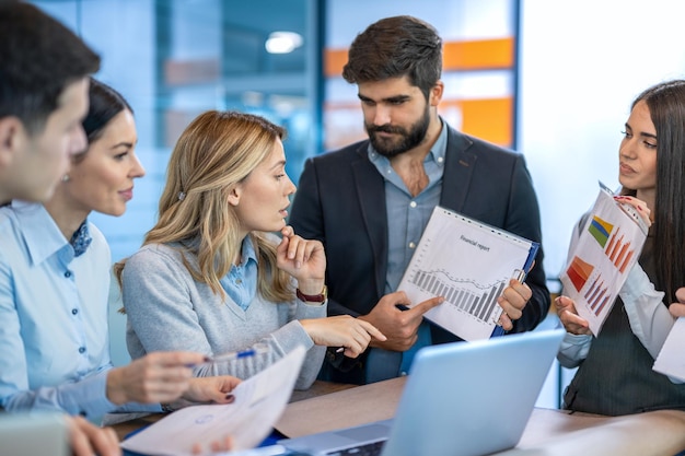 Het boekhoudteam bespreekt de gegevens van de financiële verslagen met een grafiek op een papieren document in het kantoor en beoordeelt de bedrijfsstrategie en de metrieken voor bedrijfsanalyse