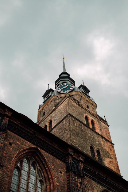 Foto het bovenste deel van de oude katholieke kerk met een klok tegen de hemel