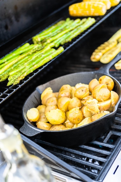 Het braden van kleine gouden aardappels in gietijzerkoekepan een openluchtgasgrill.