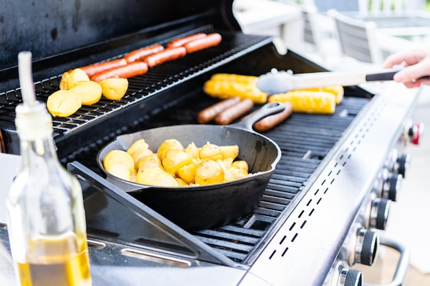 Het braden van kleine gouden aardappels in gietijzerkoekepan een openluchtgasgrill.