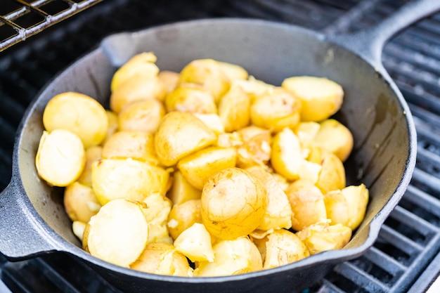Het braden van kleine gouden aardappels in gietijzerkoekepan een openluchtgasgrill.