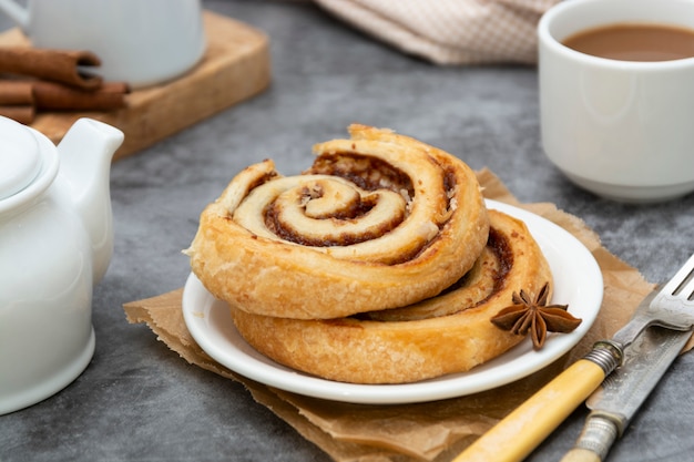 Het broodje van het kaneelbroodje dicht omhoog. Kaneel swirl gebak voor het ontbijt op grijs