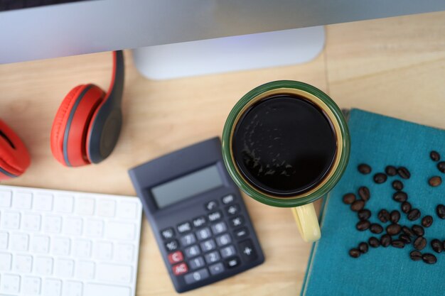 Het bureau heeft een koffiekopje en rode koptelefoons en kantoorbenodigdheden