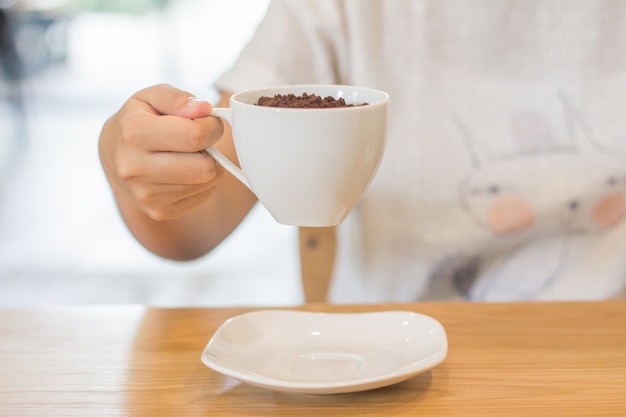 Het cacaopoeder en het witte glas in vrouwen dienen koffiewinkel in