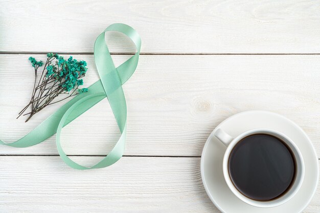 Het cijfer acht gemaakt van een satijnen lint, het boeket en een kopje koffie op een lichte houten achtergrond