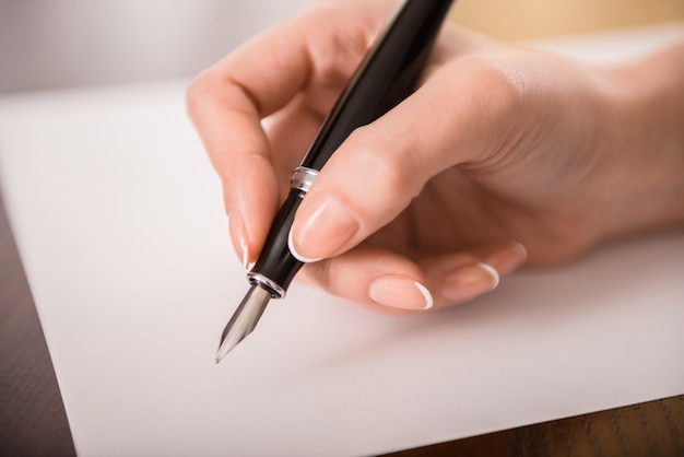 Het close-up van de hand van de vrouw schrijft op papier.