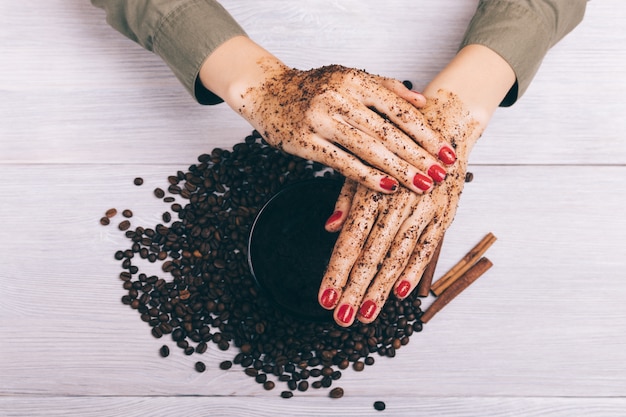 Het close-up van vrouwelijke handen past koffie toe schrobt