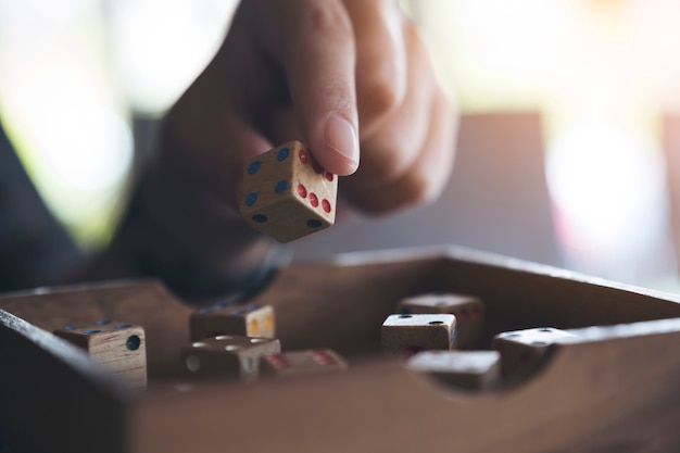 Foto het close-upbeeld van hand die en houten spelen houdt dobbelt