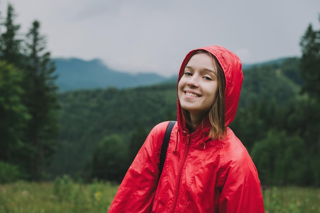 Het close-upportret van een vrolijke mooie jonge vrouw in een rood jasje met capuchon poseert