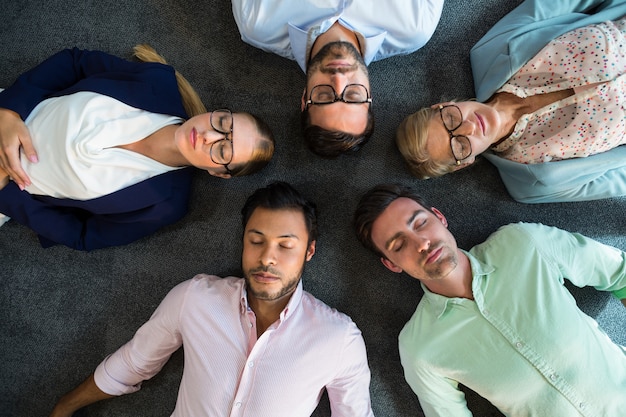 Het commerciële team met ogen sloot samen het liggen op de vloer met hoofd