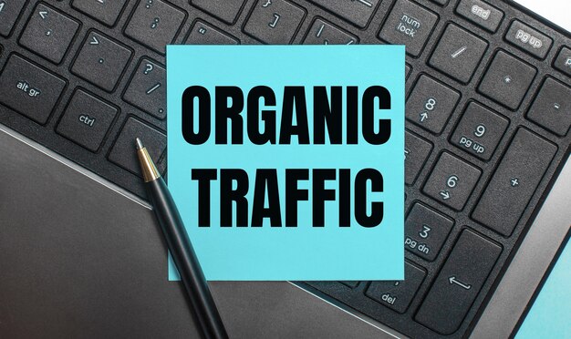 Het computertoetsenbord heeft een pen en een blauwe sticker met de tekst organic traffic