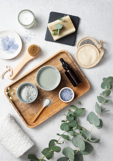 Het concept van biologische cosmetica met klei zeezout zeep borstel en eucalyptus tak in een houten dienblad op een witte gestructureerde achtergrond bovenaanzicht