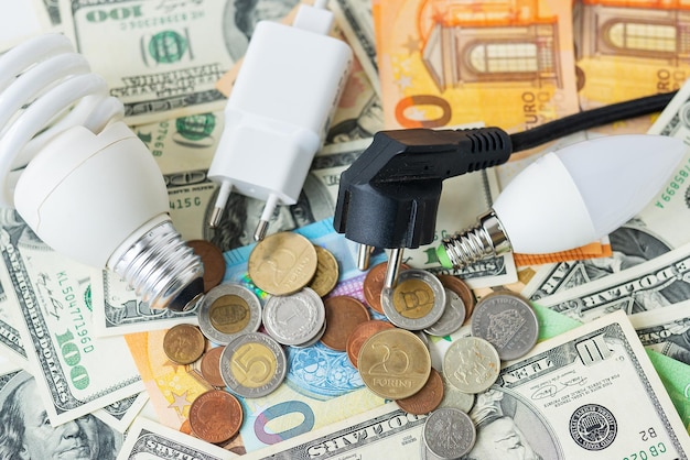 Het concept van de energiecrisis prijsstijgingen Euro- en dollarbankbiljettenmunten op de achtergrond van een lampstekkersnoer Rekenmachine voor het tellen van belastingtijdrekeningen