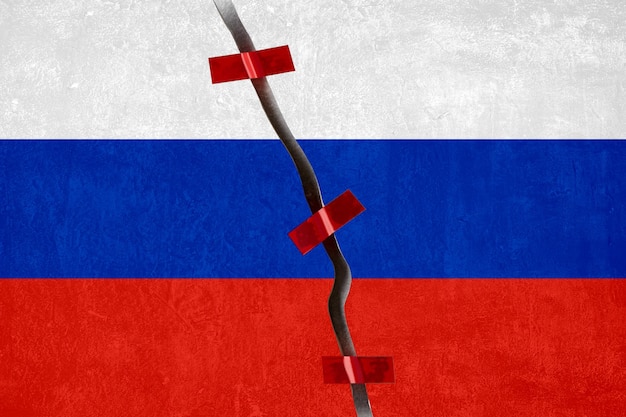 Het concept van de fragmentatie van de samenleving gebrek aan cohesie en separatisme Gebroken betonnen achtergrond met een geschilderde Russische vlag vastgemaakt met rode plakband