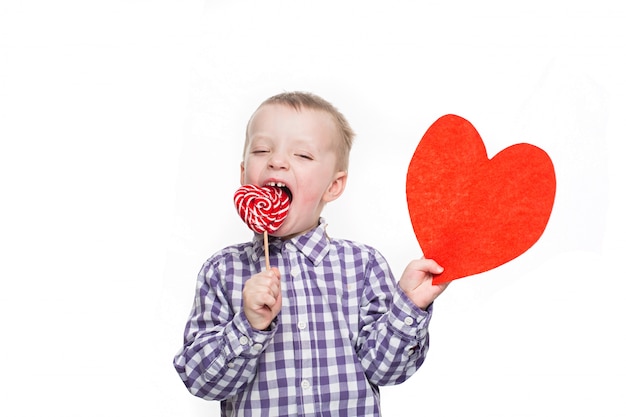 Foto het concept van de valentijnskaartendag - kleine jongen met rood hart. geïsoleerd op studio witte achtergrond