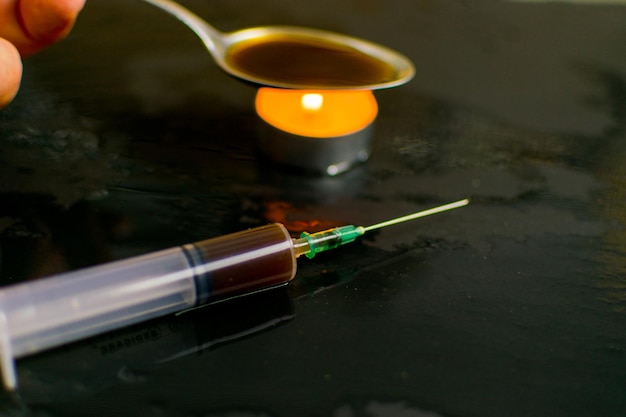 Het concept van drugsverslaving Achtergrond van het beeld van een spuit met een medicijn wazig in donkere tinten voorbereiding van een medicijn