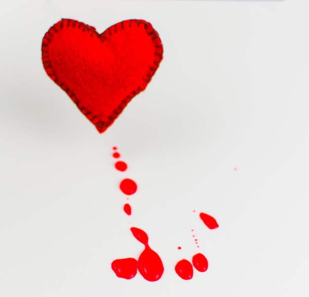 Het concept van een bloedend hart Gestikte hart- en bloedvlekken op een witte achtergrond