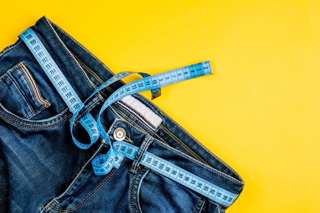 Het concept van een gezonde levensstijl en voeding Blue jeans met een blauw meetlint in plaats van een riem