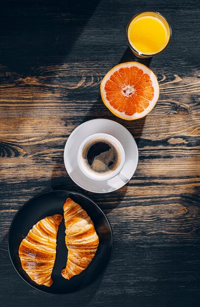 Het concept van een uitgebreid en gevarieerd ontbijt Twee croissants koffie sinaasappelsap en grapefruit