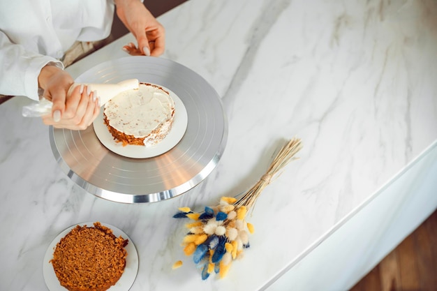 Foto het concept van het bakken van snoepjes vrouw die een taart maakt in de keuken het proces van het maken van een bento taart