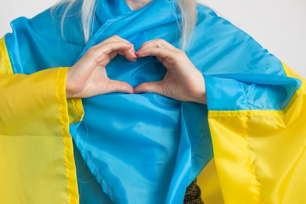 Het concept van het beëindigen van de oorlog in Oekraïne. hart in de kleuren van de vlag van Oekraïne in vrouwelijke handen.