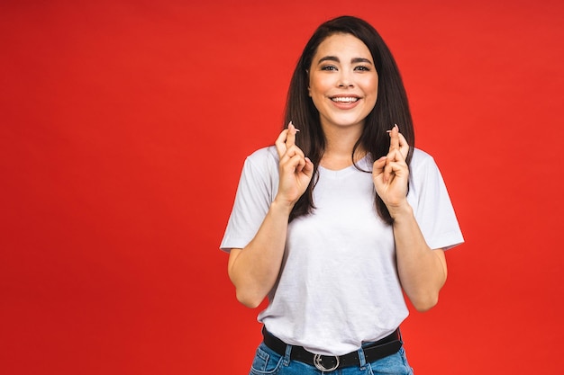 Het concept van meditatie Een mooie jonge vrouw staat in een meditatieve pose geniet van een rustige sfeer houdt haar handen vast in een gebedsgebaar geïsoleerd op rode achtergrond