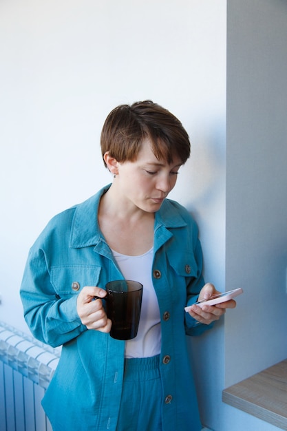 Het concept van werkgelegenheid, interviews, reclame voor digitale technologie - vrouw die koffie drinkt en aan de telefoon spreekt. De glimlachende vrouw met kop belt. Ochtend van meisje