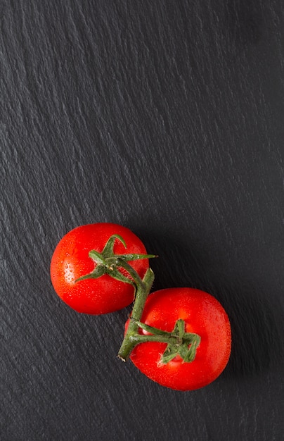 Het concepten organische tomaten van het voedsel op zwarte leiraad met exemplaarruimte