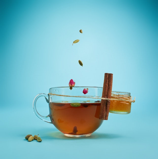 Het conceptuele beeld van kopje kruidenthee, honing, citroen op een blauwe achtergrond