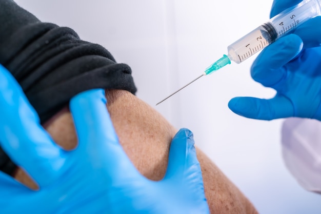 Het coronavirusvaccin injecteren bij een oude dame, antilichamen, de bevolking immuniseren.