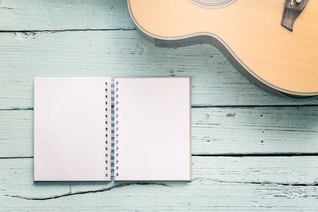 Het dagboek blanco met een akoestische gitaar op de houten tafel van muziek componist voor muzieknoten achtergrond