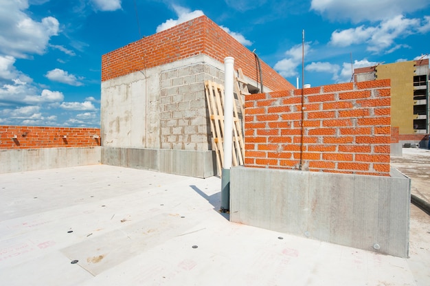 het dak van een nieuw huis in aanbouw met een bakstenen muur van een monolithisch huis