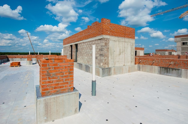 het dak van een nieuw huis in aanbouw met een bakstenen muur van een monolithisch huis