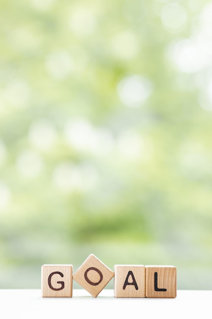 Het doelwoord is geschreven op houten kubussen op een groene zomerachtergrond Close-up van houten elementen