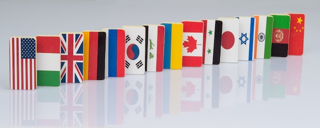 Het domino-effect met tegels van vlaggen van verschillende landen van de wereld Politieke spellen