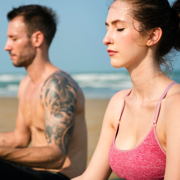 Het echtpaar doet een yoga op het strand