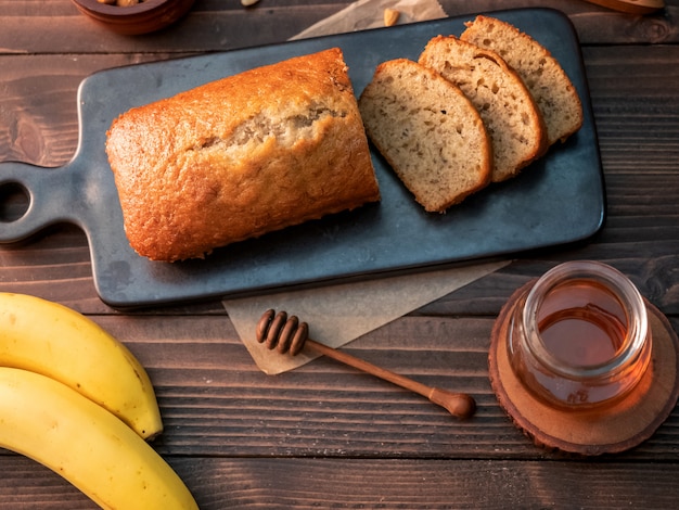 Het eigengemaakte die pond van het banaanbrood met cashewnoten en honing op houten lijst wordt gesneden.