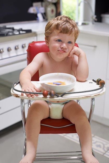 Het eten van peuter en jongen in de stoel voor voedsel voeding of maaltijd in de keuken van het huis of thuis voor ontbijt hongerig kind baby denken en gezond kind met schaal voor voeding natuurlijk dieet of groei alleen