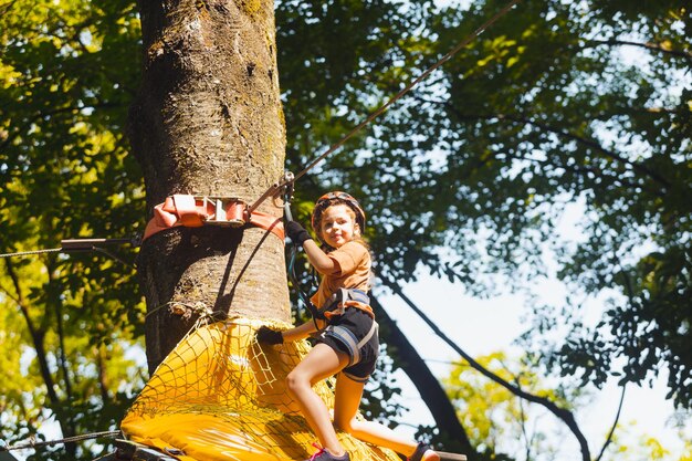 Het geconcentreerde meisje overwint voorzichtig obstakels in het touwpark