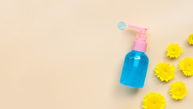 Het gel van het alcoholhanddesinfecterend middel in pompfles met gele bloem op room