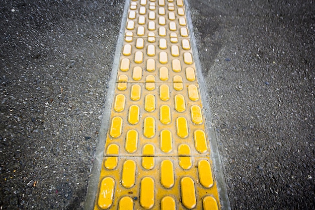 Het gele brailleblok op de loopbrug