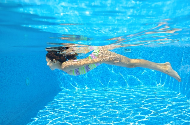 Het gelukkige actieve kind zwemt onderwater in pool