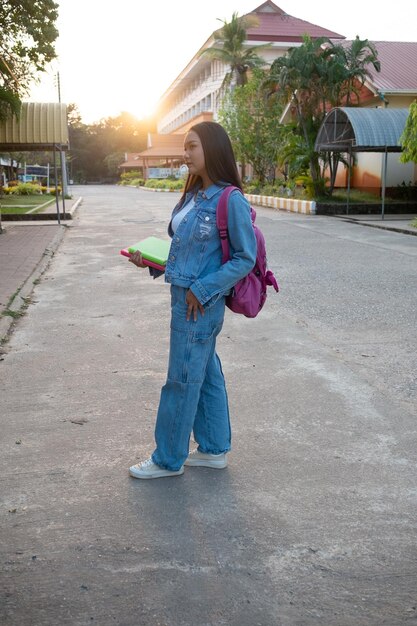 Het gelukkige jonge boek van de meisjesgreep met rugzak die op school lopen