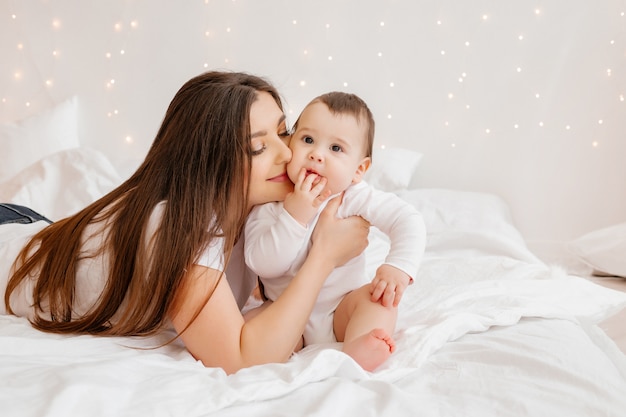 Het gelukkige jonge mamma koestert peuter in bed